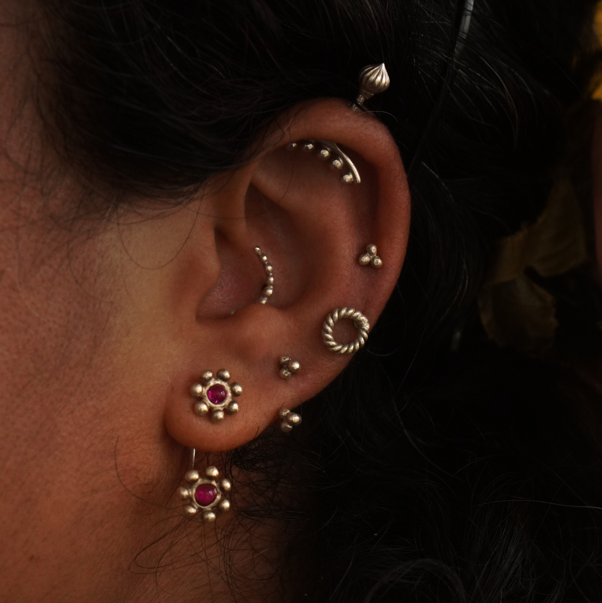 Ear styled with multiple piercings — helix, conch, tragus, lobe